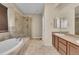 Bathroom showcasing a soaking tub, glass-enclosed shower, and tile flooring at 9816 Kalispell St, Commerce City, CO 80022
