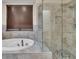 Bright bathroom featuring tile floors, soaking tub, and glass enclosed shower at 9816 Kalispell St, Commerce City, CO 80022