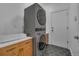 A modern laundry room with stacked washer and dryer and black tiled flooring at 9816 Kalispell St, Commerce City, CO 80022