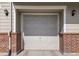 The garage door, framed by brick accents and wall-mounted lights, adding architectural detail to the exterior at 13181 Grant W Cir # B, Thornton, CO 80241