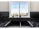 Close-up of kitchen sink with black countertops and subway tile backsplash with a view to the outdoors at 13181 Grant W Cir # B, Thornton, CO 80241
