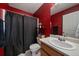 Bathroom showcasing a shower with a black curtain, single sink vanity, and red walls at 10752 Steele St, Northglenn, CO 80233