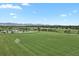 An aerial view showcasing a large soccer field with a goal post, pond, and mountain backdrop on a clear day at 11151 W 53Rd Dr, Wheat Ridge, CO 80033