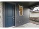Close-up of a home's front entry featuring a modern blue door, gray siding, and a sleek digital lock at 11151 W 53Rd Dr, Wheat Ridge, CO 80033