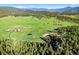 Sprawling green landscape with houses, barns, a horse area, ponds and mountains in the distance at 6150 Bluebell Ln, Evergreen, CO 80439