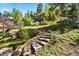 Stone steps lead through lush greenery and rock formations to the beautiful backyard at 6150 Bluebell Ln, Evergreen, CO 80439
