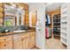 Bright bathroom with a stone-tiled countertop, wood cabinets, and an adjacent walk-in closet at 6150 Bluebell Ln, Evergreen, CO 80439