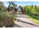 Stunning log home features a stone foundation, attached garage, and natural landscaping at 6150 Bluebell Ln, Evergreen, CO 80439
