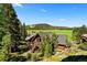 Scenic log home with deck surrounded by lush greenery, set against a backdrop of rolling hills at 6150 Bluebell Ln, Evergreen, CO 80439