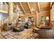 Spacious living room features log walls, a tree-trunk column, and spiral stairs with an open floorplan at 6150 Bluebell Ln, Evergreen, CO 80439