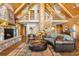 Grand living room with stone fireplace, a tree-trunk column, and log-cabin walls exudes rustic elegance at 6150 Bluebell Ln, Evergreen, CO 80439