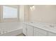 Bright bathroom featuring double vanity with white countertops and a tub under a window at 1850 Sawtooth Mountain Dr, Berthoud, CO 80513
