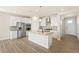 Modern kitchen featuring white cabinets, stainless steel appliances, an island with a sink, and wood-look floors at 1850 Sawtooth Mountain Dr, Berthoud, CO 80513