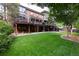 Spacious backyard with a lush green lawn, patio, a multilevel deck, and mature trees at 8047 S Fairfax Ct, Centennial, CO 80122