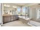 A bright main bathroom is showcased, featuring double sinks, a tub, a walk-in shower, and large windows at 16360 Paris Way, Brighton, CO 80602