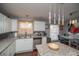 Bright kitchen with white cabinets, granite countertops, stainless steel appliances, and modern lighting at 1571 Sheridan Blvd, Lakewood, CO 80214