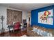 Eclectic living room featuring hardwood floors, a colorful piano painting, and an arcade game at 1571 Sheridan Blvd, Lakewood, CO 80214