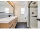 Modern bathroom featuring sleek vanity, large mirror, and frameless glass shower enclosure at 3166 W Indian Summer Ln, Castle Rock, CO 80109