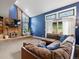 Inviting living room featuring a blue accent wall, a cozy fireplace, and a comfortable brown sofa at 5860 W Atlantic Dr, Lakewood, CO 80227