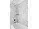 Modern bathroom with white tub and stylish gray marble-patterned tile surround at 15977 Red Bud Dr, Parker, CO 80134