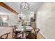 Inviting dining area with a modern chandelier, light wood floors and open access to the updated kitchen at 201 Wright St # 106, Lakewood, CO 80228