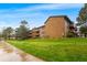 Well-maintained brown brick apartment building with lush green lawn and mature trees at 201 Wright St # 106, Lakewood, CO 80228