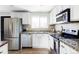 Bright kitchen features stainless steel appliances, granite counters, tile backsplash, and white cabinets at 13055 E Dakota Ave, Aurora, CO 80012