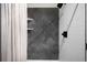 A tiled shower features dark accent tiles, a shower curtain, and a built-in shelf at 2179 S Bannock St, Denver, CO 80223
