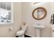 Cozy half bathroom featuring a pedestal sink, decorative mirror, and toilet at 7844 Grady Cir, Castle Rock, CO 80108