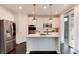 Modern white kitchen with stainless steel appliances, island and hardwood floors at 7844 Grady Cir, Castle Rock, CO 80108