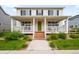 Charming home featuring a inviting covered porch, green door, white siding and manicured landscaping at 12845 Park Creek Way Way, Firestone, CO 80504