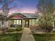 Inviting single-story home with stone accents, a covered porch, and lush landscaping at dusk at 19834 W 56Th Pl, Golden, CO 80403