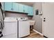Bright laundry room with light blue cabinets, washer, dryer, and utility sink at 6651 Yale Dr, Highlands Ranch, CO 80130