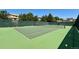 A verdant, well-maintained tennis court is surrounded by tall trees and fencing at 12054 E Lake Cir, Greenwood Village, CO 80111