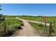 Scenic walking trail with a 'pets must be leashed' sign, meandering through lush green fields and wildflowers at 12054 E Lake Cir, Greenwood Village, CO 80111