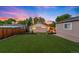 A perfectly manicured backyard featuring lush grass, landscaped garden beds, and charming string lights in the evening at 5125 Umatilla St, Denver, CO 80221
