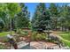 Seating area with stone patio, fountain, lush landscaping, mature trees and blue sky at 1999 Champions Cir, Castle Rock, CO 80104