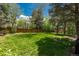 Lush backyard featuring a well-manicured lawn, mature trees, and a sturdy wooden fence at 7076 S Niagara Ct, Centennial, CO 80112