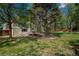 Serene backyard with a lush lawn, mature trees, and a charming seating area at 7076 S Niagara Ct, Centennial, CO 80112