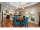 Sunny dining area with French doors, view into kitchen, and stylish blue chairs around a round table at 7076 S Niagara Ct, Centennial, CO 80112