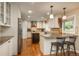 Modern kitchen featuring granite countertops, stainless steel appliances, central island, and adjacent bar seating area at 7076 S Niagara Ct, Centennial, CO 80112