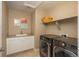 Modern laundry room with front-load washer/dryer, utility sink, and built-in shelving at 7076 S Niagara Ct, Centennial, CO 80112