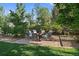 Landscaped backyard featuring an outdoor seating area with a stone patio surrounded by lush trees at 9375 Webster Way, Westminster, CO 80021