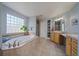 A spacious bathroom featuring a large tub, glass block window, and vanity area at 9375 Webster Way, Westminster, CO 80021