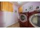 Modern laundry room featuring red front loading machines and built in upper cabinets at 9375 Webster Way, Westminster, CO 80021