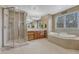 Bathroom featuring a glass enclosed shower, jetted tub, dual sinks and vanity, and large mirror at 8707 Windhaven Dr, Parker, CO 80134