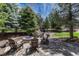 Inviting outdoor fire pit area with stone surround and comfortable seating, surrounded by mature trees at 8707 Windhaven Dr, Parker, CO 80134
