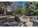 Outdoor patio with stone fire pit, seating area, and mature trees at 8707 Windhaven Dr, Parker, CO 80134
