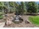 Outdoor water feature with small waterfall, rock landscaping and lush greenery creating a peaceful oasis at 8707 Windhaven Dr, Parker, CO 80134
