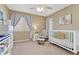 Bedroom featuring carpeted floors, a ceiling fan, a crib, and a window with curtains at 10375 Knollside Dr, Parker, CO 80134